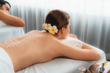 Lüks spa salonlarında sıcak mum ışığında cilt bakımı gören mutlu çift müşterisi. Sağlık kaplıcasında güzellik tedavisiyle tuz temizliği. Sessiz.