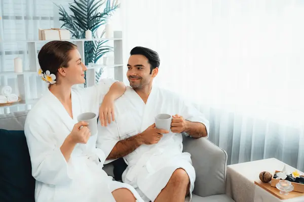 stock image Beauty or body treatment spa salon vacation lifestyle concept with couple wearing bathrobe relaxing with drinks in luxurious hotel spa or resort room. Vacation and leisure relaxation. Quiescent