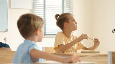 Beyaz bir çocuk ödevlerini yaparken ve açıklama dinlerken güzel bir öğretmen sınavı açıklıyor. Sınıfta not alırken ya da kağıda cevap yazarken öğretmenine bakan sevimli bir çocuk. Pedagoji.