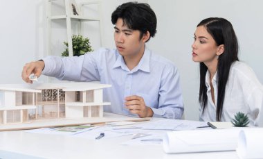 Kooperatif mühendis ekibinin portresi ev modelini ölçmek için cetvel ve mimari ekipmanlar kullanarak birlikte çalışıyor. Yaratıcı iş tasarımı ve takım çalışması konsepti. Tertemiz...