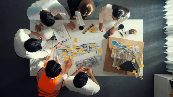 Top down view of skilled engineer team talking while looking at project plan. Aerial view of group of smart interior designer working together and planning for engineering construction. Alimentation.