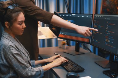 Modern ofisteki neon ışık odasında bilgi ağını gösteren dizüstü bilgisayarla iki ekranda veri çalıştıran akıllı web sitesi geliştirme kodlayıcı sistemini tartışan IT geliştiricilerinin ciddiyeti. İnfobahn.