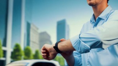 İş adamı, ESG yeşil parktan akıllı saat hologram şarj şarjının EV araba aküsü durumunu kontrol et. Modern şehir yaşam tarzı ve karbondioksiti azaltmak için çevre dostu elektrikli araba kullanımı. İnceleyin