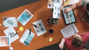 Proje yöneticisi renk paletleri seçerken tasarımcının tablete baktığı yukarıdan aşağıya hava görüntüsü. Profesyonel grafik tasarımının en üst görüntüsü ve logoya bakın. Yetenekli ekip grafikleri seçiyor. Sempozyum.