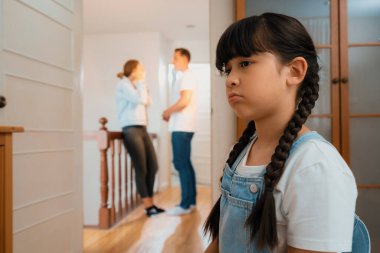 Stresli ve mutsuz genç kız arka planda ebeveynleri tartışırken köşede ağlayıp üzülüyor. Evde aile içi şiddet ve travmatik çocukluk depresyona dönüşür. Eşzamanlama