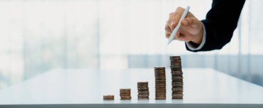 Büyüyen madeni para yığını iş yatırımını ve ekonomik büyümeyi simgeliyor. Finansal hedefe ulaşmak ve maksimum kâr sağlamak için finansal planlama yapan iş adamları. Kurnaz.