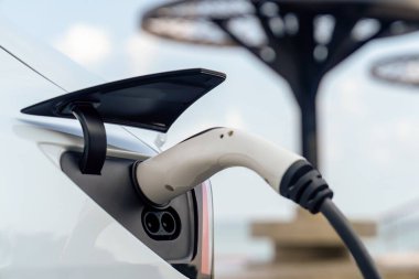 Kapalı EV şarj kolu fişe takıldı veya elektrikli arabaya bağlandı, EV araba aküsünü temiz çevre için sıfır CO2 emisyonu ile alternatif ve sürdürülebilir enerjiyle şarj etti. Kalıcı