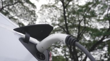 Green City Park 'taki otoparkta yavaş çekim EV elektrikli araba şarj bataryası. Sürdürülebilir ve çevre dostu şehir yolculuğu için yenilenebilir otomobil için alternatif temiz enerji teknolojisi. Yararlı