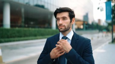 Profesyonel iş adamı yolda yürürken kravatı ayarlar. Yönetici şehre bakarken takım elbise giyiyor. Yatırımcı görüşmeye gitmeden önce kendini kontrol etmiş. Arka plan bulanık. Sevinçli..