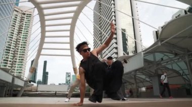 Asyalı hippiler şehir merkezinde alçak açılı kamerayla çevrili insanlar tarafından ayak sesleri çıkarırken profesyonel çok kültürlü dansçılar neşelenin. Break dans konsepti. Açık hava sporu 2024. Yumuşak bir şekilde..