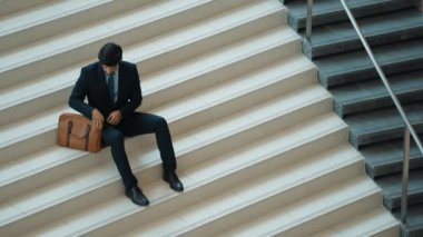 Akıllı bir iş adamının iş planı yapmak için telefon ve dizüstü bilgisayar kullanması. Merdivenlerde otururken. Müdür terfi alıyor, bilgisayarla arkadaşlarını ararken satışları arttırıyor. Sevinçli..