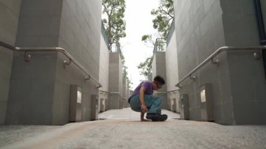 Profesyonel break dansçı dar koridorda sokak dansı yapıyor. Yetenekli mutlu Asyalı hipster, B-boy 'a dar duvarda adım gösterirken müziğe geçiyor. Modern yaşam tarzı. Açık hava sporu 2024. Yumuşak bir şekilde..