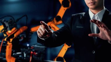 XAI Mühendisi, fabrikadaki robot kolu kontrol etmek için siber robot yazılım kullanıyor. IOT yazılımı kullanarak internet ağına bağlı uzmanlar tarafından kontrol edilen otomasyon üretim süreci.