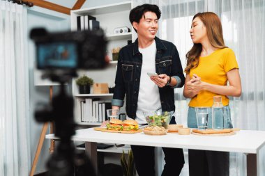 Aşçılar, sosyal medya yemek programı kanalı canlı yayın menü yemeği salatası, kepekli çörek ve video kameradan hamburger kaydı için telefonda yorum okuyorlar. İnfobahn.