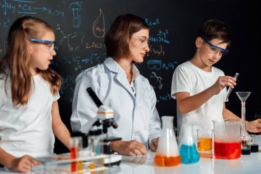 Laboratuvarda çalışan öğretmen, güvenlik gözlüğü takıyor, STEM sınıfında kimya bilimi üzerine deney yapıyor. Öğrenci komedisi tüpte sıvı deneyi yapar. Etkinlik.