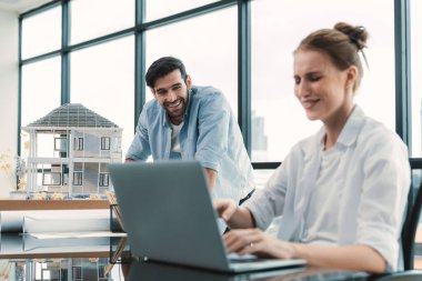 Genç yetenekli proje yöneticisi, modern ofis veya mimarlık stüdyosundaki proje planını kullanarak, Kafkas mühendisi ev modunu incelerken dizüstü bilgisayar kullanarak çalışıyor. İnşaat mühendisliği, yaratıcı tasarım. İzleme.