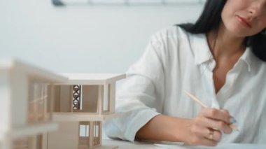 Modern ofisteki ev modelini planla ölçmek için kalem işaretleme noktası ve cetvel kullanmaya odaklanan genç ve güzel mimar mühendisinin yakın çekimi. Yaratıcı tasarım ve mimar konsepti. Tertemiz..