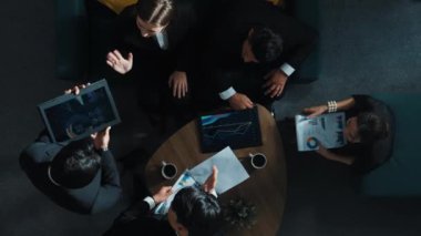 Profesyonel iş adamının yukarıdan aşağıya hava görüntüsü yatırımcıya iş belgesi dağıtırken, yönetici tablet görüntüleme istatistiklerini masaya koydu ve sunumu dinledi. Müdürlük.