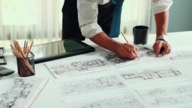 Taslak ve dizüstü bilgisayarda ayakta duran ve yazan akıllı bir mühendis. Mimarların elleri toplantı masasında ekipmanlarla birlikte yaratıcı bina inşaatını planlayıp düşünüyor. Hizalama.