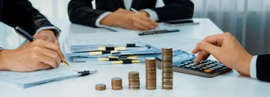 Büyüyen madeni para yığını iş yatırımını ve ekonomik büyümeyi simgeliyor. Finansal hedefe ulaşmak ve maksimum kâr sağlamak için finansal planlama yapan iş adamları. Kurnaz.