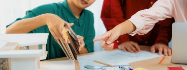 Akıllı iç mimar, ev modeli ve mimari döküman dağınıklığı ile toplantı masasındaki renk örnekleri ve ev modeli arasındaki rengi karşılaştırır. Yaratıcı çalışma konsepti. Değiştirilmiş