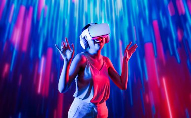 Zeki bir kadın, metaevreni birbirine bağlayan VR kulaklık takan neon ışıklarla çevrili duruyor. Gelecekteki siber uzay topluluğu teknolojisi. Zarif bir kadın dans etmekten, dans etmekten ve şarkı söylemekten hoşlanır. Halüsinasyon.