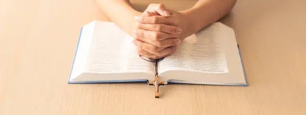 在木制桌旁的圣经上 有祈祷的男性手持十字架的剪影 顶部视图 基督教和上帝祝福的概念 温暖和棕色的背景 — 图库照片