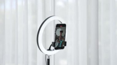 Arkadan bakıldığında kadın nüfuzlu kişi canlı yayın vlog görüntülerini çeker. Önemli sosyal medya ya da blogu gizler. Stüdyo ışıklandırmalı bir kız çevrimiçi pazarlama oturumu yayını için.