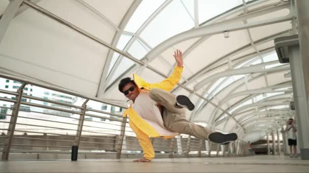 回廊でヘッドスピンを使用しながらハンサムな幸せなアジアのヒップスターダンス ダンサーや振付師がストリートダンスをしながらカメラを見ている フリースタイルの歌 アウトドアスポーツ 2024 スプライトリー — ストック動画