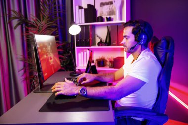 Kulaklık takan akıllı oyun flaması hafta sonu neon dijital siber ışıklandırma odasında son yaşam tarzı yarışmasında şampiyon olmak için bilgisayar ekranında araba yarışı oynamaktan zevk alır. Tahmin et..