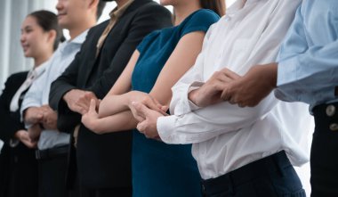 Mutlu ve gülümseyen çok ırklı ofis çalışanı, sinerjiyi ve ticari başarı için işbirliğini destekleyen bir kuyrukta el ele tutuşuyor. Modern işyerinde çeşitli profesyonel ofis çalışanları arasında bağ var. Uyum