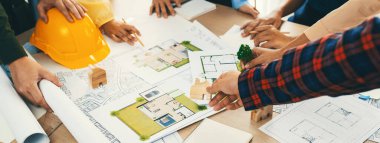 Profesyonel mimar, eko ev projesinde yeşil tasarım kullanımını planlı ve mimari ekipmanlarla tartışan mühendis ile işbirliği yapıyor. - Yakın çekim. Tanımlama.