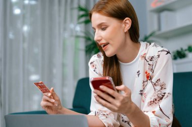 Genç mutlu kadın internetten alışveriş yaparak ürün satın alırken aynı zamanda internet üzerinden online ödeme sistemi ile çevrimiçi mağaza platformundan en yüksek siber güvenlik tarafından korunan ürünler sipariş ediyor.