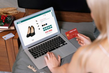Genç bir kadın internet bankacılığı için kredi kartıyla dizüstü bilgisayar kullanıyor. Evinde online ödeme kapısı ile E ticareti yapıyor. Banka kartıyla modern ve kullanışlı online alışveriş. Blithe