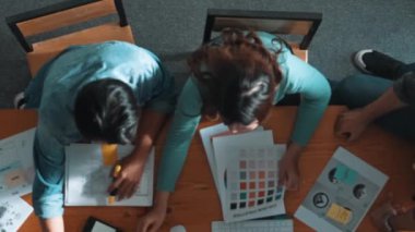 Ekip toplantısına katılıp fikir hakkında konuşurken proje yöneticisinin yazma fikrinin en üst görüntüsü. Renk paletine bakarken ve kağıda fikir yazarken profesyonel tasarımcı logosu. Sempozyum.