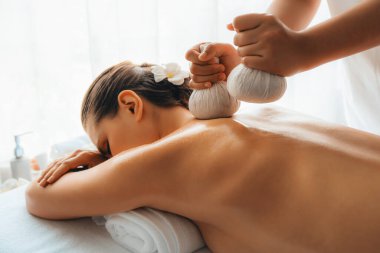 Sıcak bitkisel top spa masaj vücut tedavisi, masör kadın vücuduna nazikçe şifalı bitki torbası bastırıyor. Aromaterapi dinlenme sükuneti ve sükuneti kaplıca salonundaki atmosferi aydınlatıyor. Sessiz.