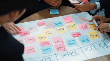 İş adamlarının işyerinde iş akışını yönetmek için sıkı yönetim kurulu kurması. Çeşitli pazarlama ekibi bir sınır çiziyor ve Kanban üzerinde çalışmak için renkli notlar kullanıyor. Kapatın. Müdürlük.