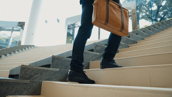 Крупный план делового человека, поднимающегося по лестнице. Успешный человек поднимается по лестнице, исследуя что-то новое. Представлял путешествие, получение повышения, поиск новой работы, повышение квалификации. Ликующий.