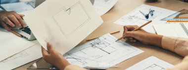 Erkek mühendis mimarlık bürosunda dizüstü bilgisayar üzerinde çalışırken, yetenekli mimar kağıt üzerinde taslak hazırlıyor. Profesyonel mühendis ve mimar mimari projede işbirliği yaparlar. - Yakın çekim. Tanımlama.