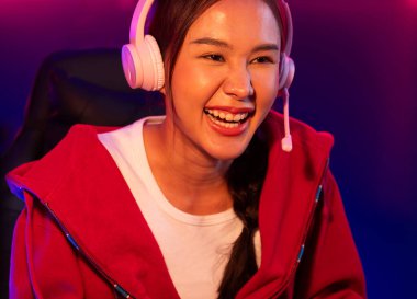 Portre sunucusu güzel Asyalı kız flamasının çevrimiçi oyun oynaması kulaklık takması pastel renkli konuşmalar izleyici medyası ile çevrimiçi. Esport yetenekli takım oyuncuları neon mavi odada. Taktik.