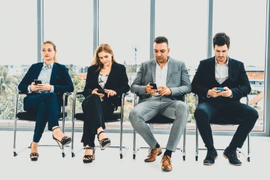 İş kadınları ve işadamları iş görüşmesi için koltuklarda beklerken cep telefonu kullanıyorlar. Şirket işi ve insan kaynakları kavramı. uds
