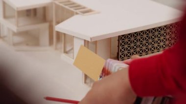 Mimari ekipman kullanarak yavaş çekim ev tasarımcısı bir plan çizerken, iç mimari tasarımcı da müşterilerin talebine göre renk örneklerinden uygun renkler seçiyor. Değiştirilmiş