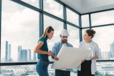 Bir grup mimar mühendis proje planına bakarken, yapı hakkında beyin fırtınası yapıyorlar. İdari ekip inşaat hakkında şehir manzaralı bir yerde dururken tartışıyor. İzleme.