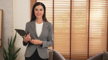 Mutlu ve gülümseyen kadın psikolog psikiyatri ofisinde ya da terapi odasında pano tutuyor. Arkadaş canlısı ve profesyonel ruh sağlığı danışmanı ya da terapisti. Blithe