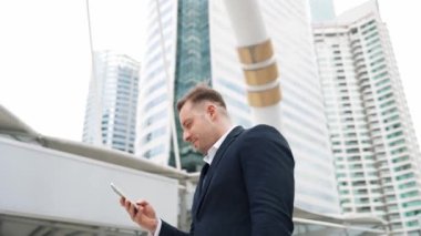 Kafkasyalı iş adamı şehir merkezinde dururken cep telefonlarını kontrol ediyor ve pazarlama ekibinden satış raporlarını inceliyor. Yetenekli bir yönetici cep telefonu üzerinde çalışıyor ve veri analizine bakıyor. Urbane.