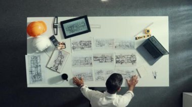 Akıllı mühendisin tablete bakarken bina yapısını analiz etmek için dizüstü bilgisayarı kullanması zaman kaybı. Proje planıyla toplantı masasında iç tasarımı kontrol eden mimarın hava görüntüsü. Hizalama.