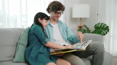 Beyaz bir baba ve tatlı bir kız kanepede otururken masal kitabı okuyorlar. Mutlu bir baba, sevimli bir Amerikan çocuğuna, birlikte zaman geçirirken hayal gücünün gelişmesi için hikaye anlatıyor. Pedagoji.