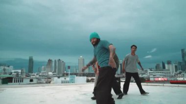 İspanyol hipster dansları şehrin mavi gökyüzü manzaralı çok kültürlü arkadaşlarıyla çevrili. Çatıda bir grup sokak dansçısı sahne alıyor. Aktif, eğlenceli, mutlu atmosfer. Açık hava sporu 2024 hiphop..
