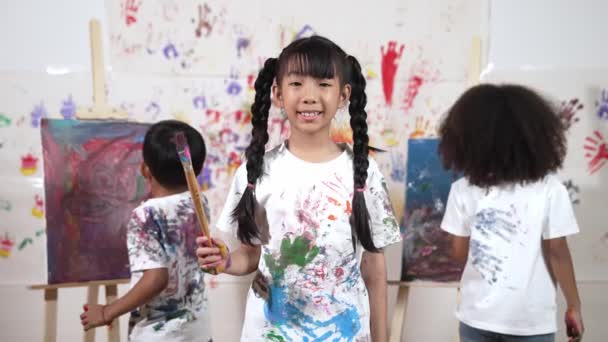 Criativo Bonito Menina Pose Câmera Enquanto Diversas Crianças Pintura Atrás — Vídeo de Stock