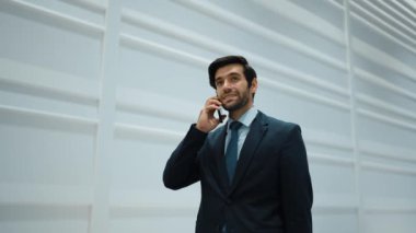 Yetenekli yönetici, iş arkadaşıyla proje hakkında konuşmak için telefon görüşmesi yapıyor. Yakışıklı erkek lider, ayakta durup kameraya bakarken satış hakkında konuşmak ve rapor vermek için iş ekibini arıyor. Sevinçli..